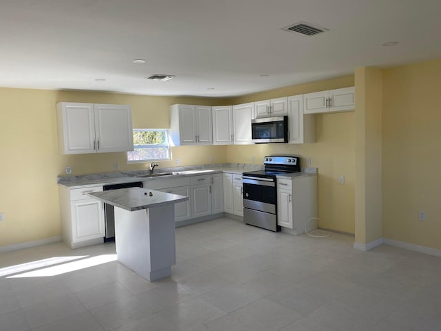 kitchen featuring white cabinets, appliances with stainless steel finishes, sink, and a center island