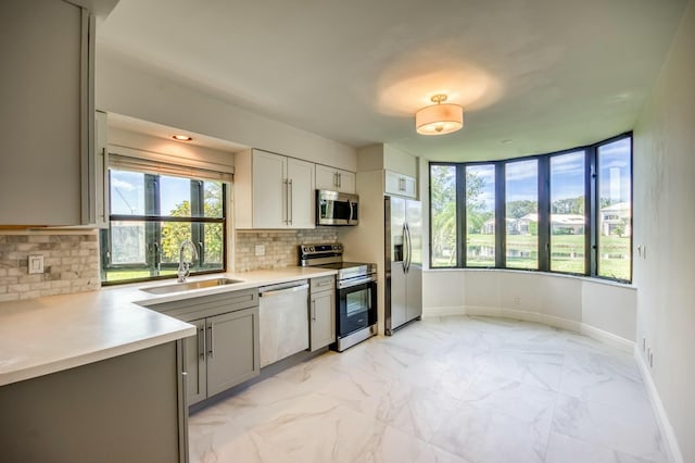 kitchen with stainless steel appliances, sink, decorative backsplash, and gray cabinetry