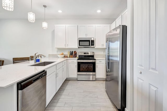 kitchen with stainless steel appliances, hanging light fixtures, sink, and kitchen peninsula