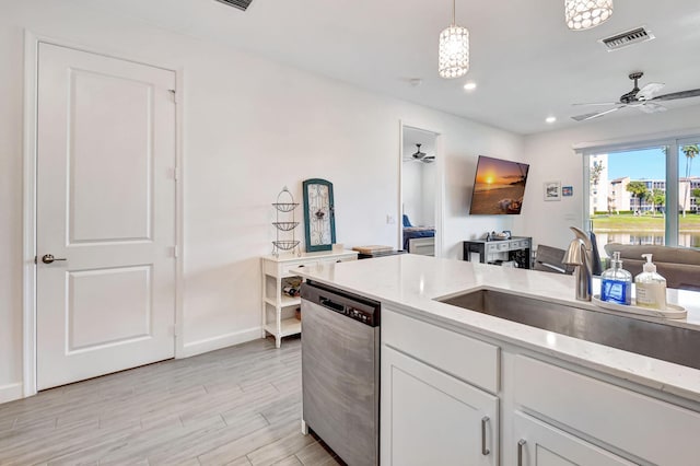 kitchen with sink, dishwasher, white cabinetry, hanging light fixtures, and light stone countertops