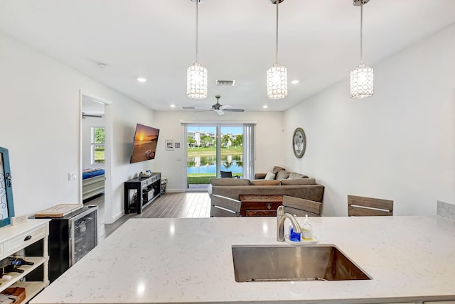 kitchen with plenty of natural light, sink, light stone counters, and decorative light fixtures