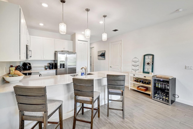 kitchen with sink, a breakfast bar, appliances with stainless steel finishes, hanging light fixtures, and white cabinets