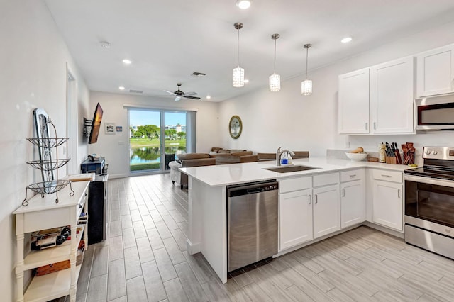 kitchen featuring sink, decorative light fixtures, appliances with stainless steel finishes, kitchen peninsula, and white cabinets