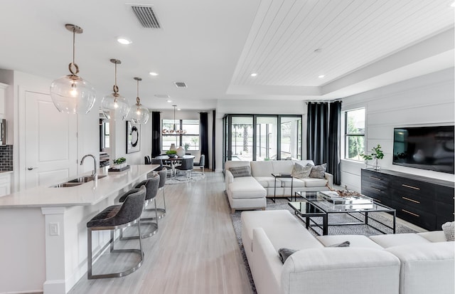 living room with a raised ceiling, plenty of natural light, sink, and wood ceiling