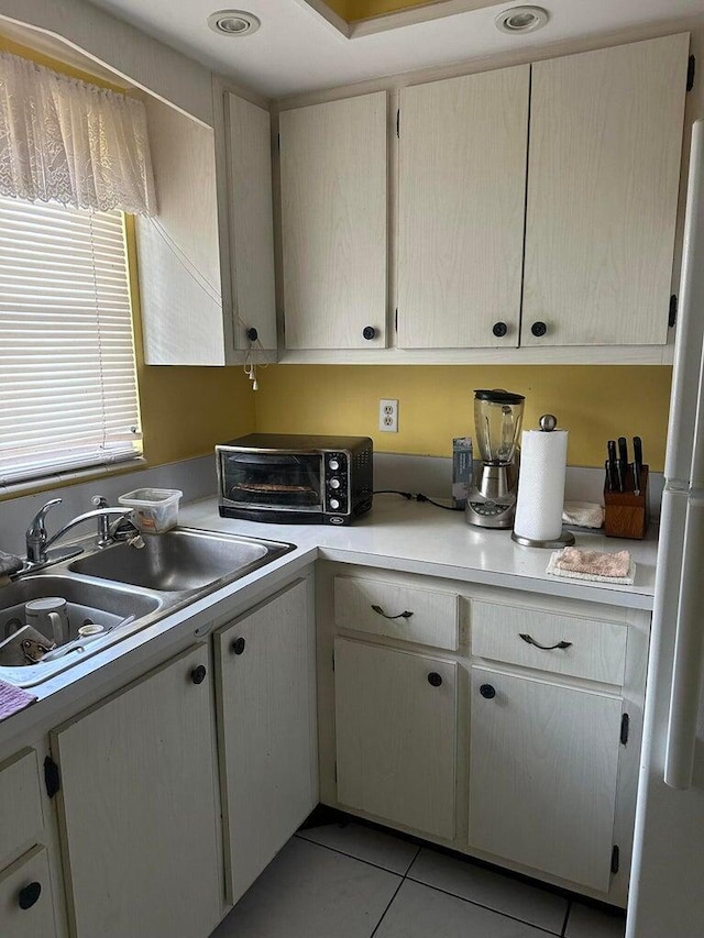 kitchen featuring sink, light tile patterned floors, and fridge