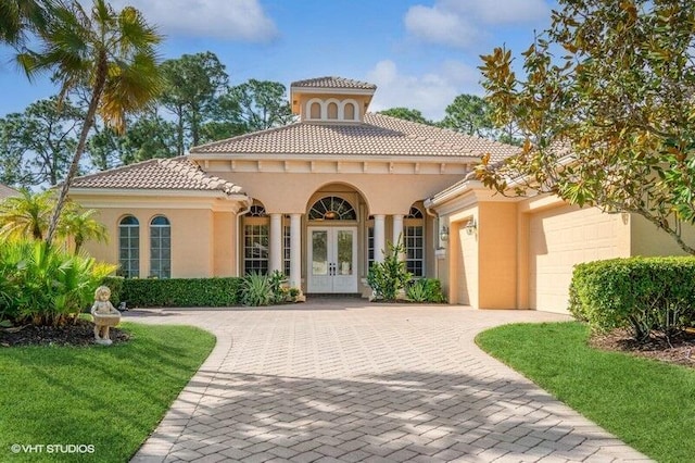 8825 Bally Bunion Rd, Port Saint Lucie, FL 34986 - mediterranean / spanish-style house with french doors, an attached garage, stucco siding, decorative driveway, and a tiled roof