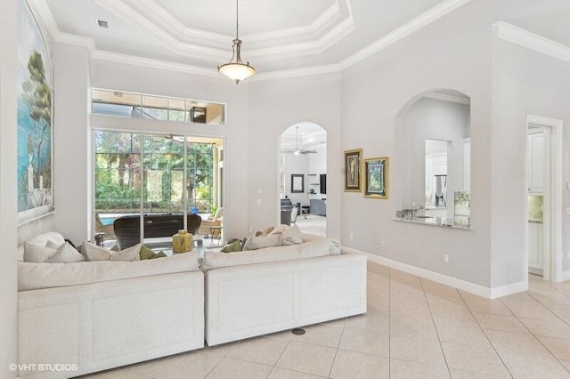 tiled living room featuring a towering ceiling, ornamental molding, a raised ceiling, and ceiling fan