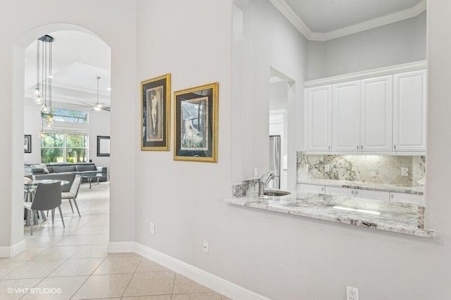 hall with ornamental molding, sink, and light tile patterned floors