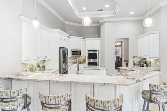 kitchen with appliances with stainless steel finishes, decorative light fixtures, and kitchen peninsula