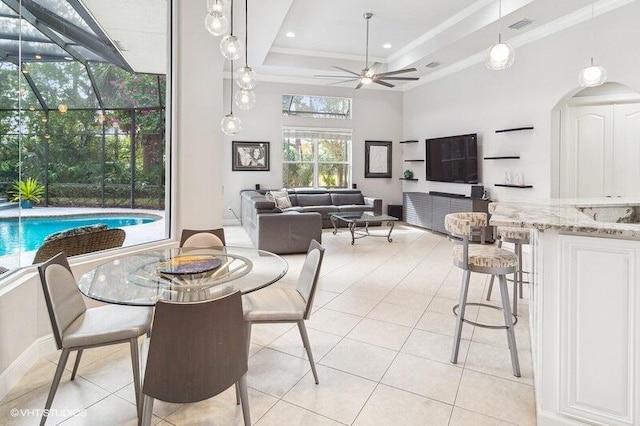 tiled dining area featuring crown molding, ceiling fan, a raised ceiling, and a towering ceiling