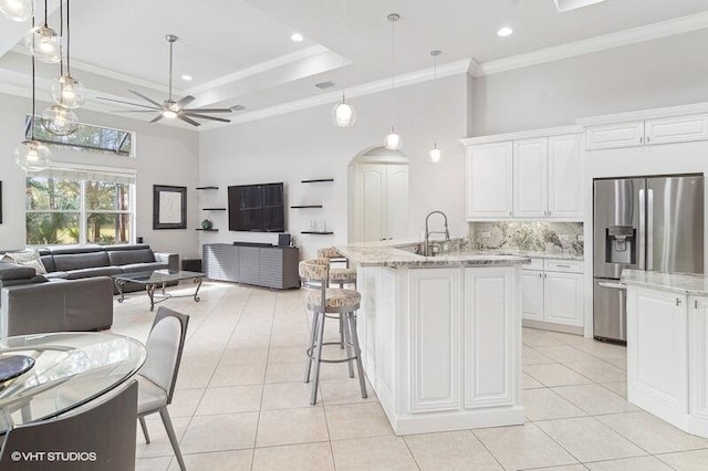 kitchen featuring light tile patterned flooring, stainless steel refrigerator with ice dispenser, white cabinetry, hanging light fixtures, and a kitchen breakfast bar