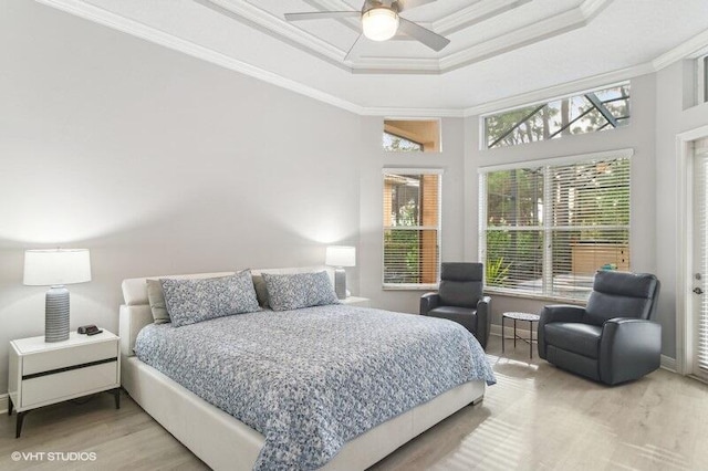 bedroom featuring ornamental molding, hardwood / wood-style floors, ceiling fan, and a tray ceiling