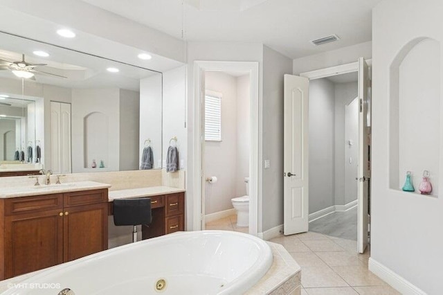 bathroom featuring tiled tub, ceiling fan, vanity, tile patterned floors, and toilet