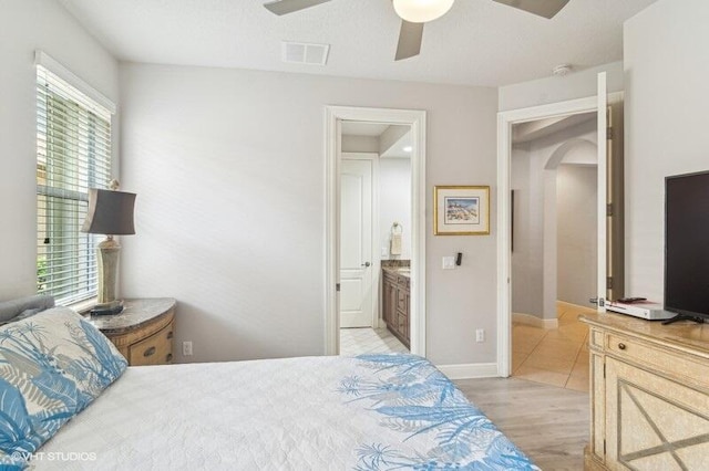 bedroom with ceiling fan, ensuite bath, and light wood-type flooring