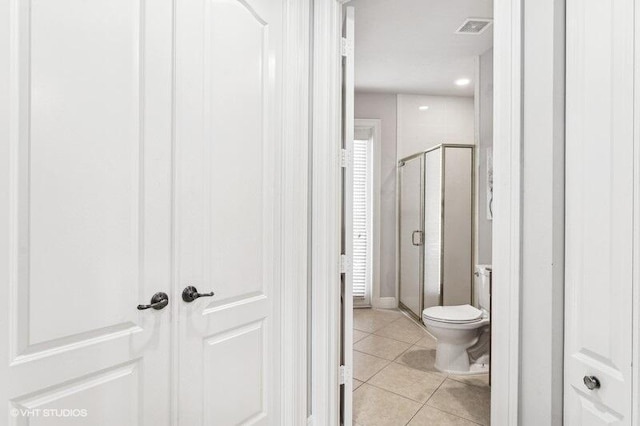 bathroom featuring a shower with shower door, tile patterned floors, and toilet