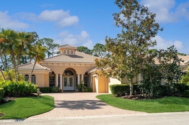 8825 Bally Bunion Rd, Port Saint Lucie, FL 34986 - mediterranean / spanish house featuring french doors, stucco siding, decorative driveway, and a front lawn