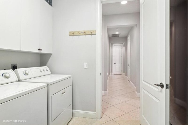 laundry room featuring cabinets, light tile patterned floors, and washing machine and clothes dryer