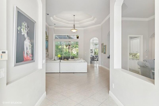 hallway with crown molding, a raised ceiling, and light tile patterned flooring