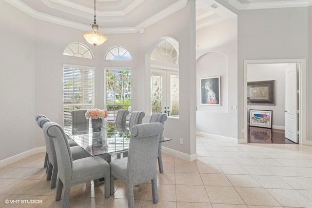 tiled dining room with a raised ceiling, crown molding, a towering ceiling, and french doors