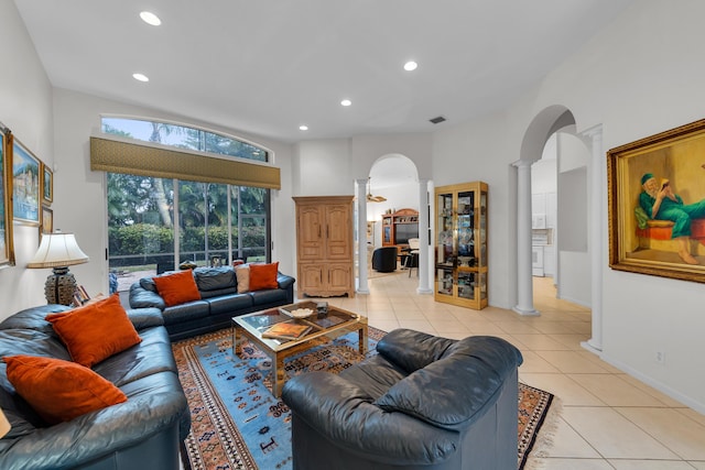 living room featuring light tile patterned floors, a towering ceiling, and ornate columns