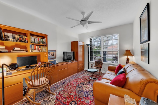 interior space featuring built in desk, a textured ceiling, and ceiling fan