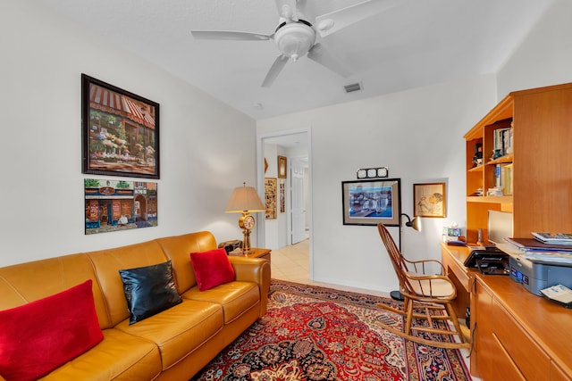 tiled living room with built in desk and ceiling fan