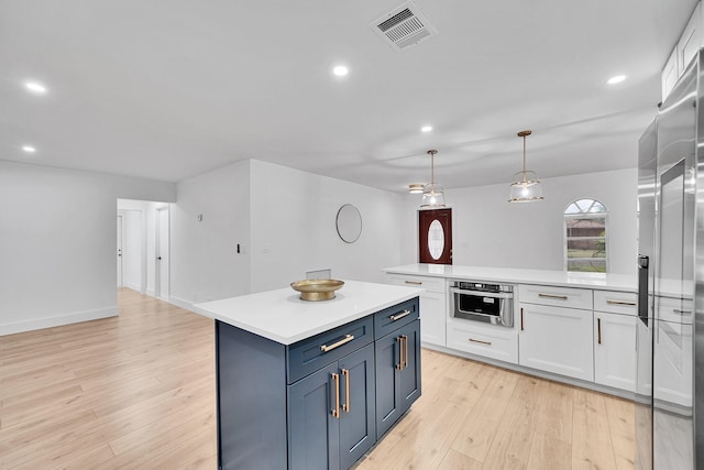 kitchen featuring white cabinets, a center island, decorative light fixtures, stainless steel appliances, and blue cabinetry