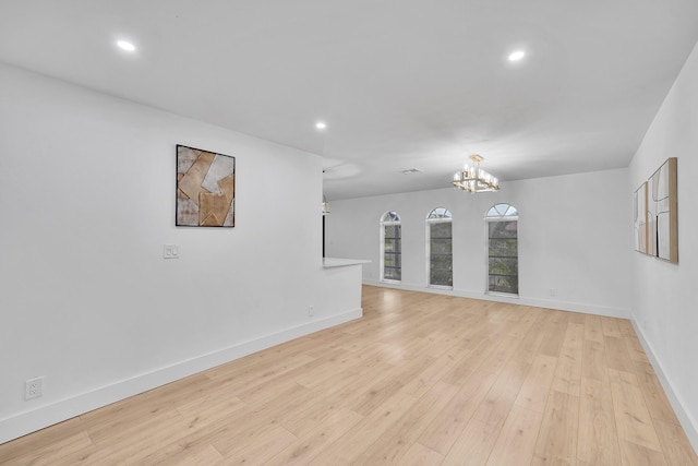 spare room with light wood-type flooring and an inviting chandelier