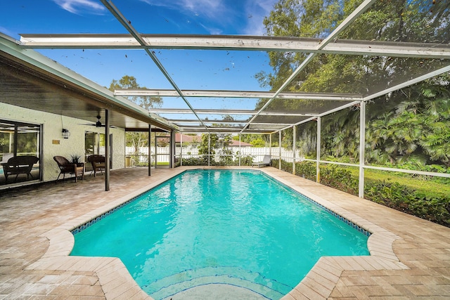 view of swimming pool with ceiling fan, glass enclosure, and a patio