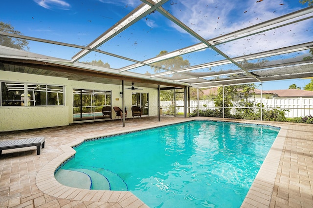 view of pool with glass enclosure, ceiling fan, and a patio