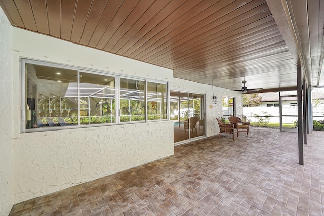 unfurnished sunroom featuring ceiling fan and plenty of natural light