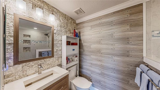 bathroom featuring a textured ceiling, toilet, vanity, and crown molding