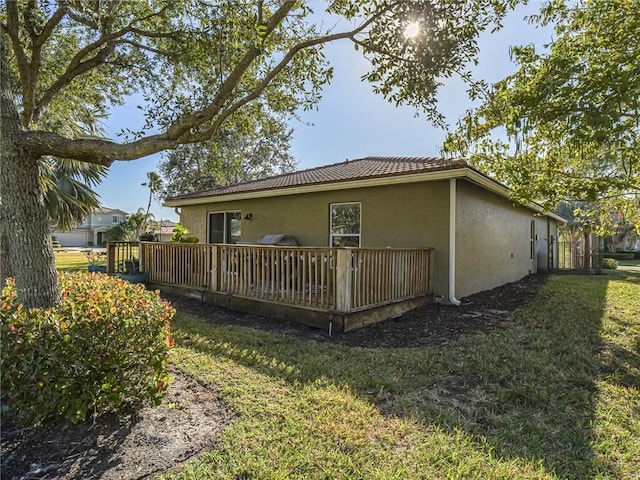 back of property with a wooden deck and a lawn