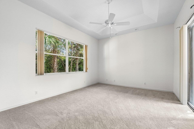 spare room with ceiling fan, a raised ceiling, and carpet flooring