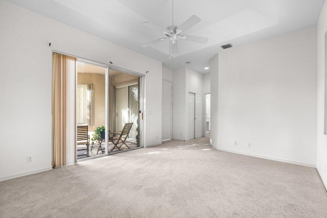 carpeted empty room featuring a tray ceiling and ceiling fan