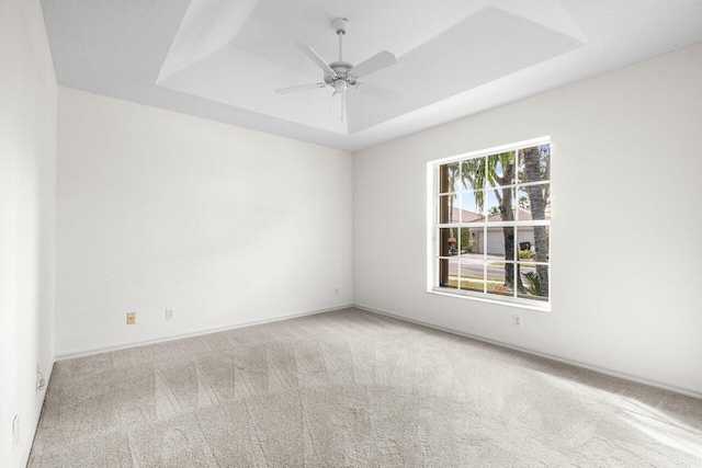 carpeted spare room featuring ceiling fan and a tray ceiling