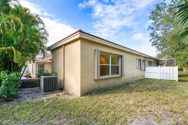 view of side of property featuring central AC unit and a lawn