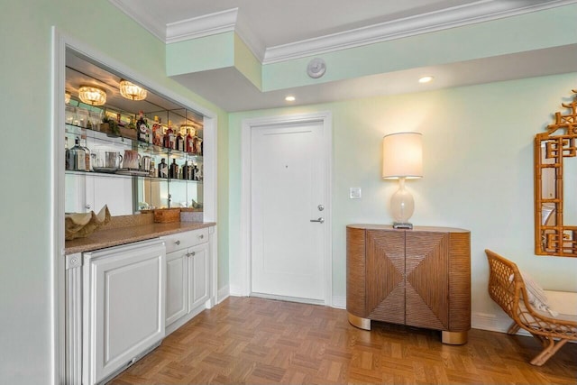 bar featuring light parquet flooring, white cabinetry, and crown molding