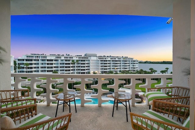 balcony at dusk featuring a water view