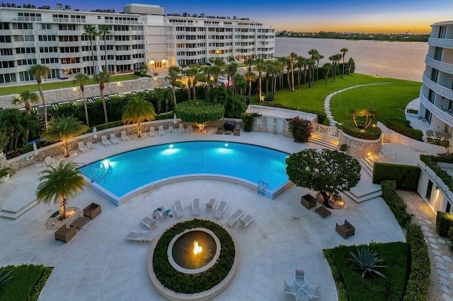 view of pool featuring a water view, a lawn, and a patio area