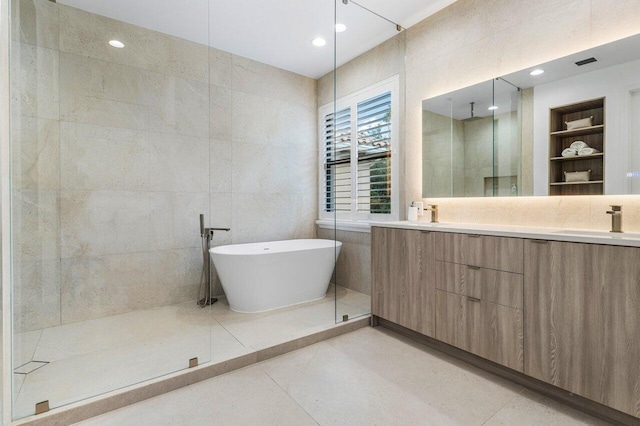 bathroom featuring built in shelves, tile patterned floors, plus walk in shower, and tile walls