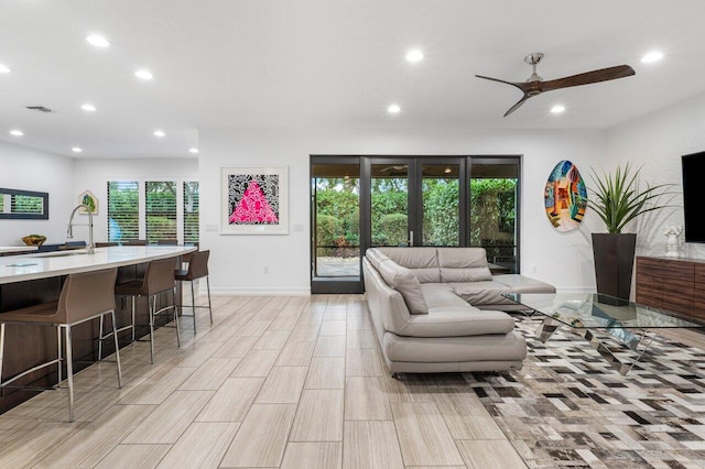 living room with sink, french doors, and ceiling fan