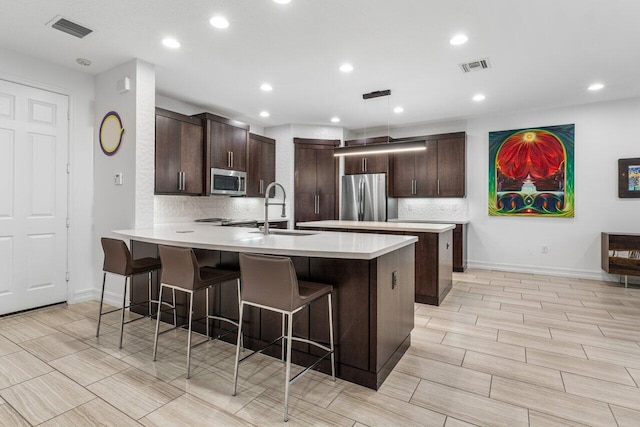 kitchen featuring appliances with stainless steel finishes, sink, backsplash, and a breakfast bar