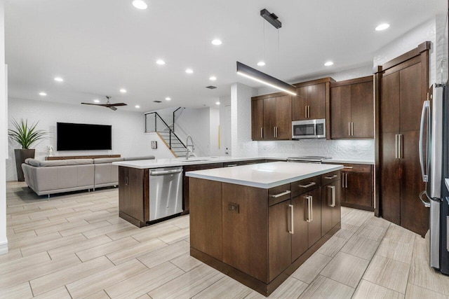 kitchen with pendant lighting, appliances with stainless steel finishes, sink, and a kitchen island