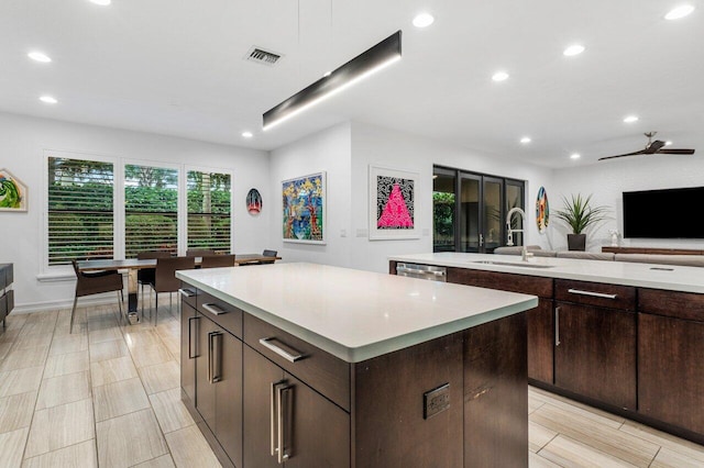 kitchen with ceiling fan, a center island, sink, and dark brown cabinetry