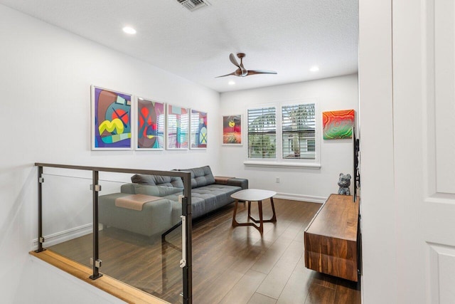 living room featuring a textured ceiling, dark wood-type flooring, and ceiling fan