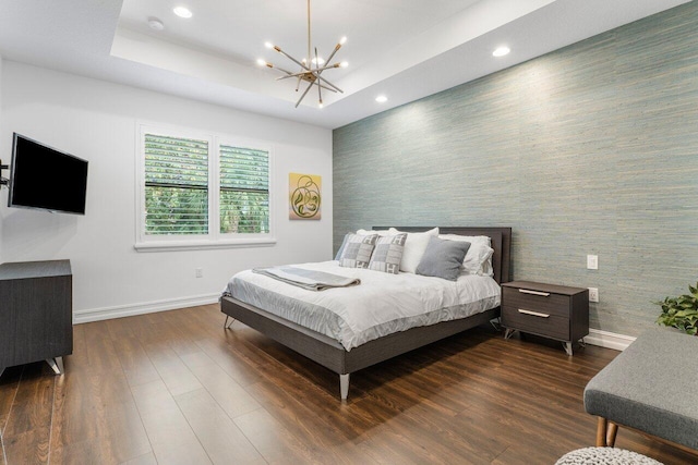 bedroom featuring dark hardwood / wood-style flooring, a notable chandelier, and a raised ceiling