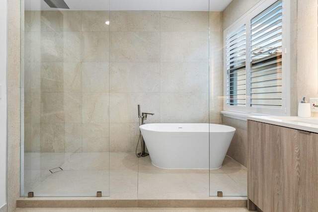 bathroom featuring vanity, plus walk in shower, and tile walls