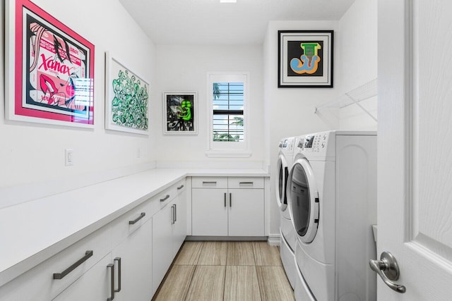 clothes washing area featuring cabinets and washer and dryer