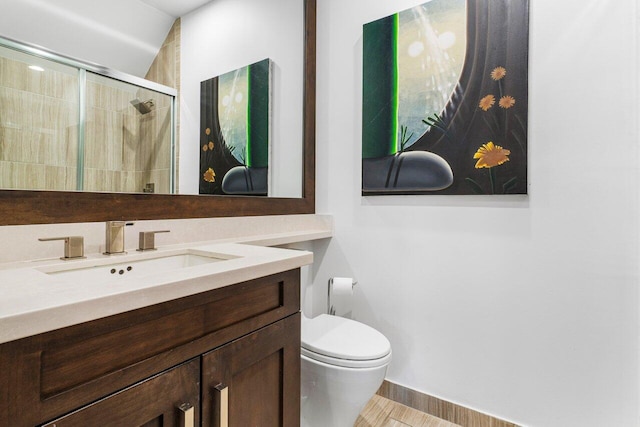 bathroom with a shower with door, vanity, and toilet